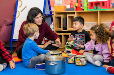 a wolf trap teaching artists is sitting with children teaching them how to play bongo drums