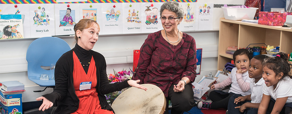 Photo depicting learning through the arts as teachers and children play a drum during a lesson