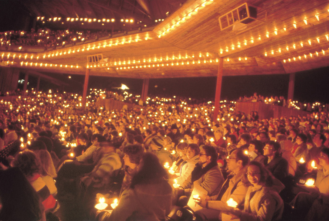 Large audience holding glowing candles during the Holiday Sing-A-Long at the Filene Center.