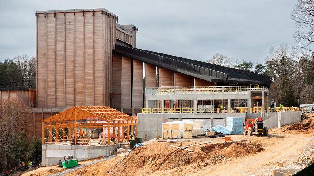 Expansive view of the Meadow Commons construction area showing a the Filene Center, new concrete structures, and workers on sloped terrain.