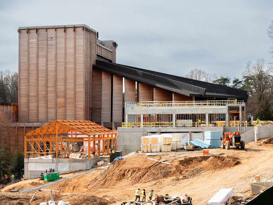 Expansive view of the Meadow Commons construction area showing a the Filene Center, new concrete structures, and workers on sloped terrain.