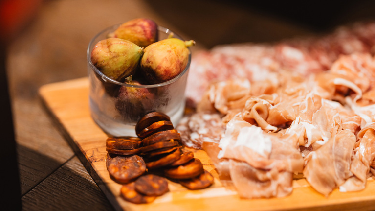 A charcuterie board with various meats and fresh figs.