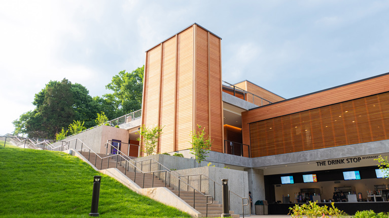 Lower-level view of Meadow Commons showing “Drink Stop” counter, stairs, and landscaped slope.