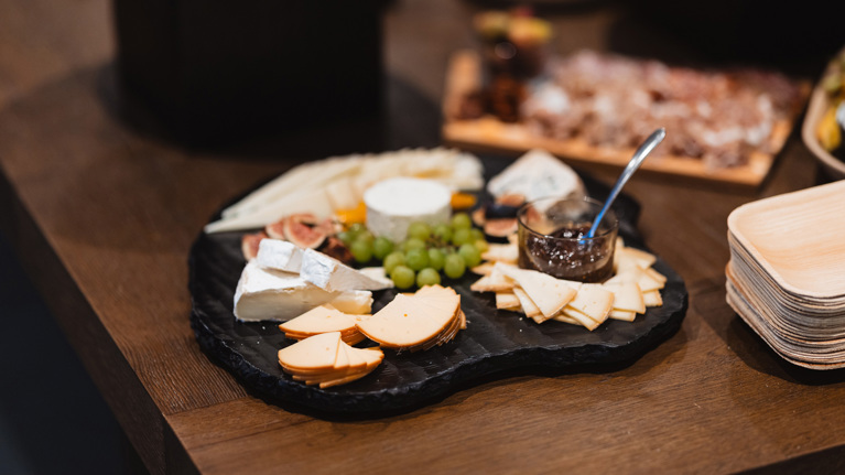 A cheese plate with grapes and fig jam.