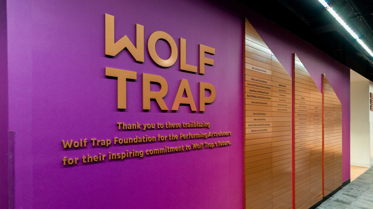 Purple donor recognition wall with “Wolf Trap” text and wooden panels listing names.