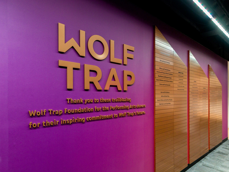 Purple donor recognition wall with “Wolf Trap” text and wooden panels listing names.