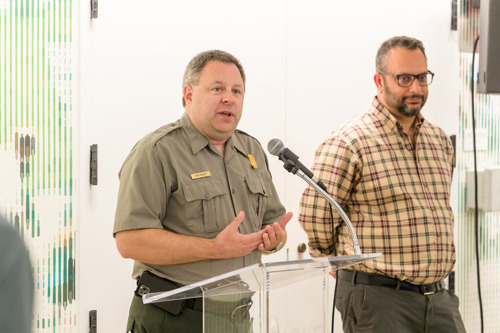 Superintendent Ken Bigly speaking at a podium with a microphone during a backstage tour, standing next to Wolf Trap President and CEO Arvind Manocha.