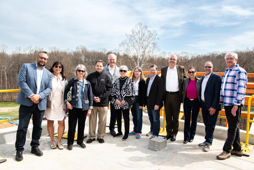 Group of campaign donors standing together on the construction site platform with trees in the background.