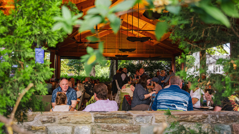 A view of Encore Circle Lounge through one of the open-air openings, surrounded by greenery.
