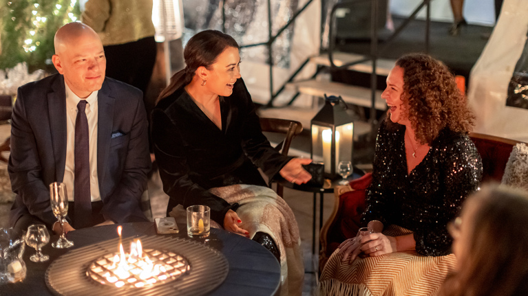 Guests talk and laugh at an outdoor firepit.