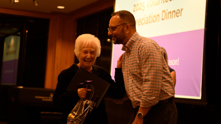 Louise Rostker smiles broadly while receiving her award from Arvind Manocha.