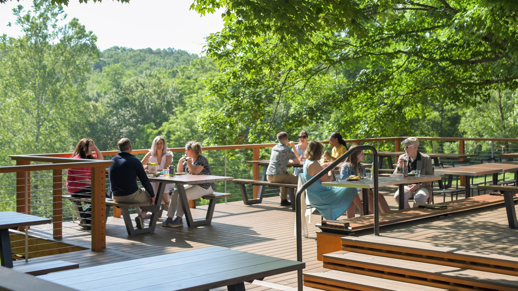 Meadow Overlook: Change from a picnic area under trees to a raised wooden deck with tables overlooking scenic greenery.