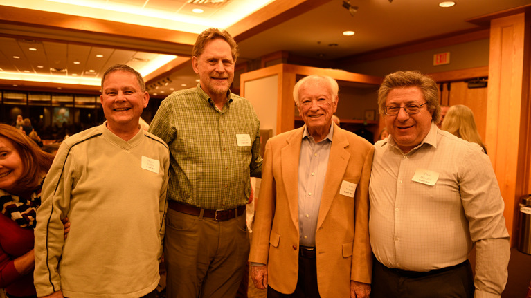Four volunteers standing side by side in the event hall.